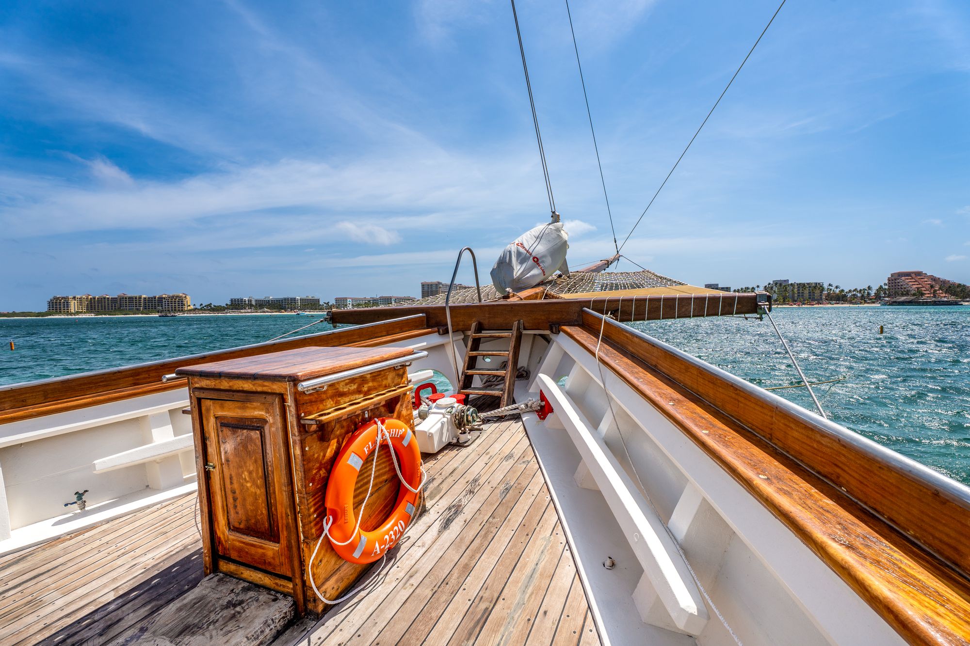 The teak foredeck of the Flagship with a Flagship life ring and Palm Beach hotels in the distance