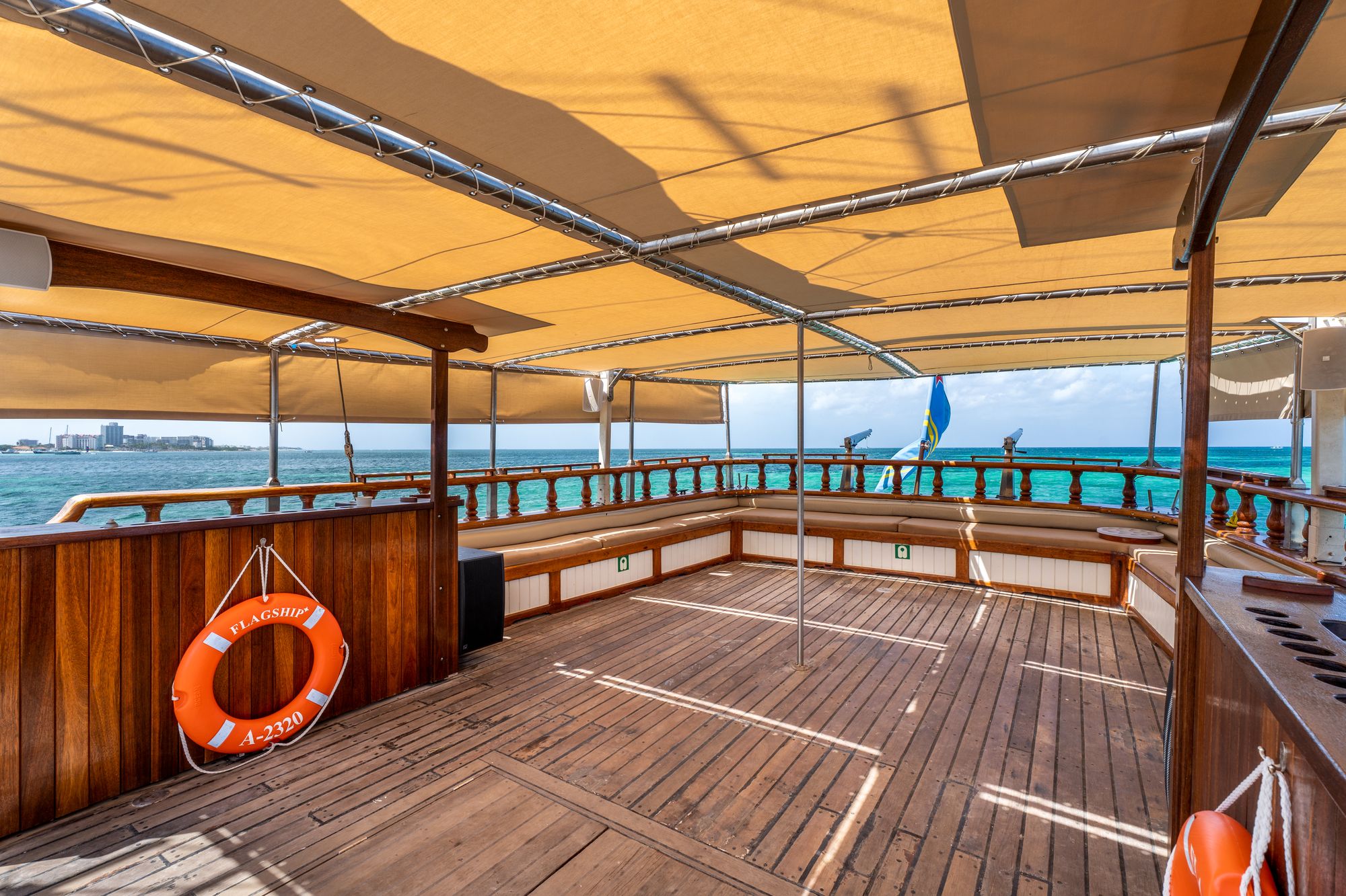 The empty covered stern deck of the Flagship with bench seating and wooden railings