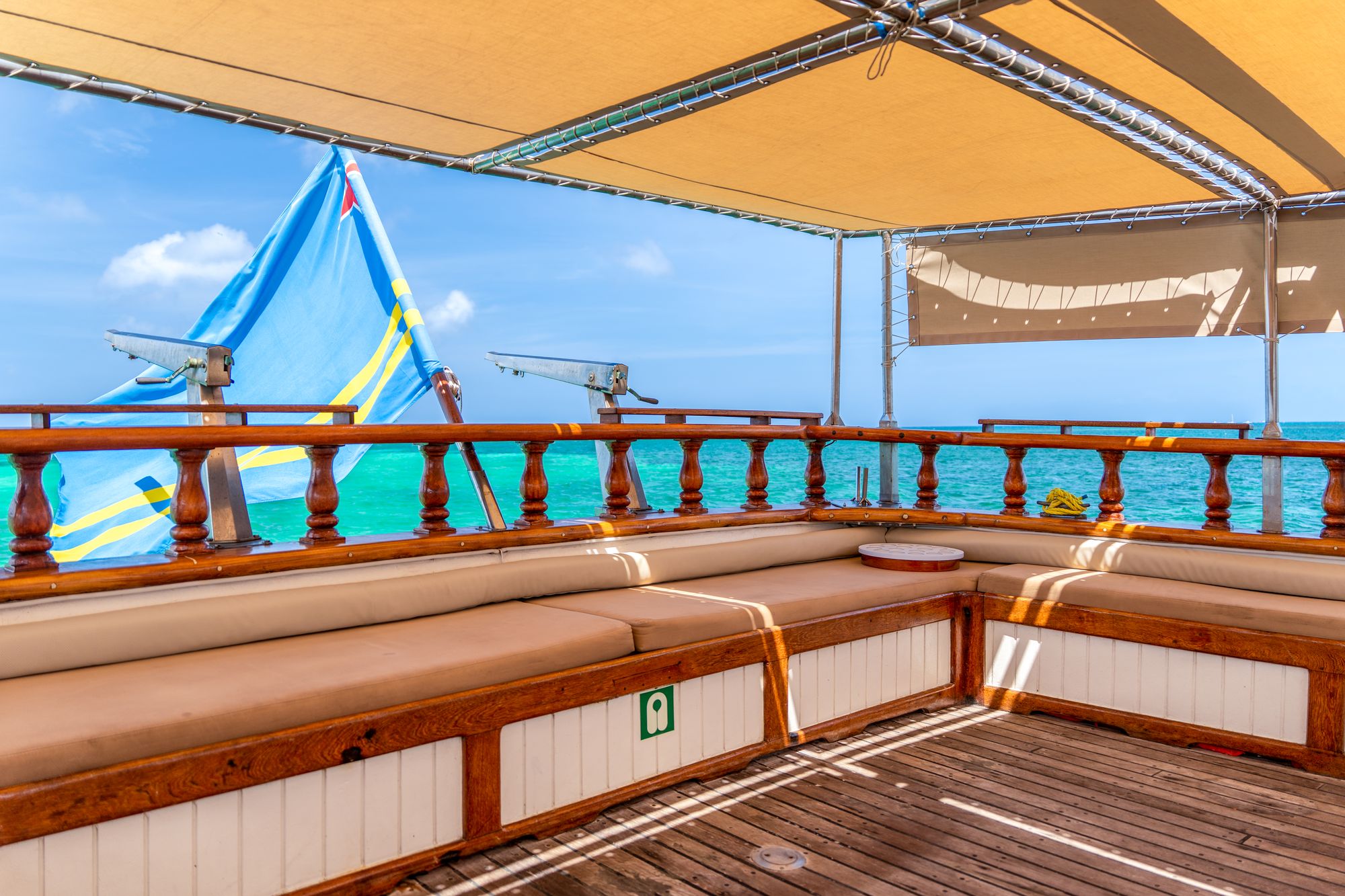 Cushioned bench seating on the stern with the Aruban flag and turquoise water behind